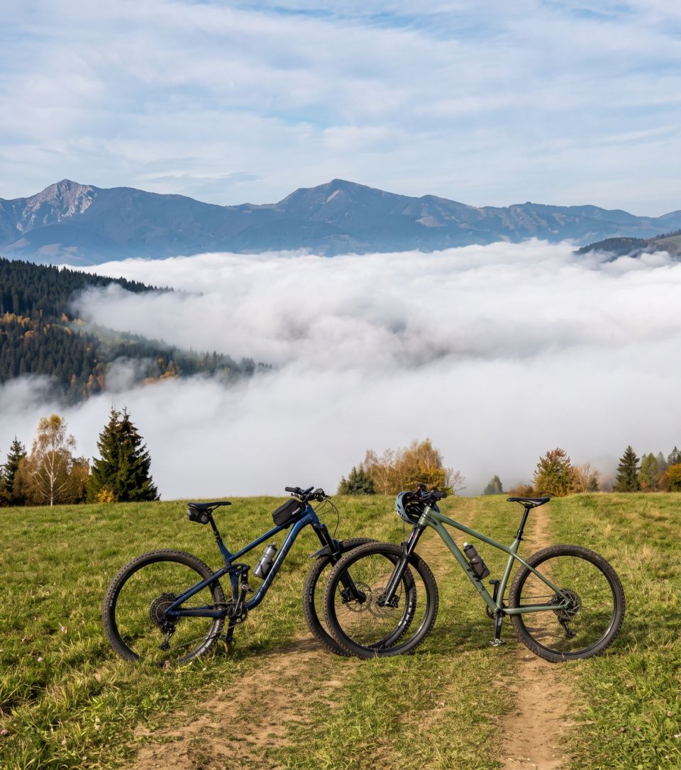 Dva horské bicykle na lúke nad hmlou s výhľadom na hory